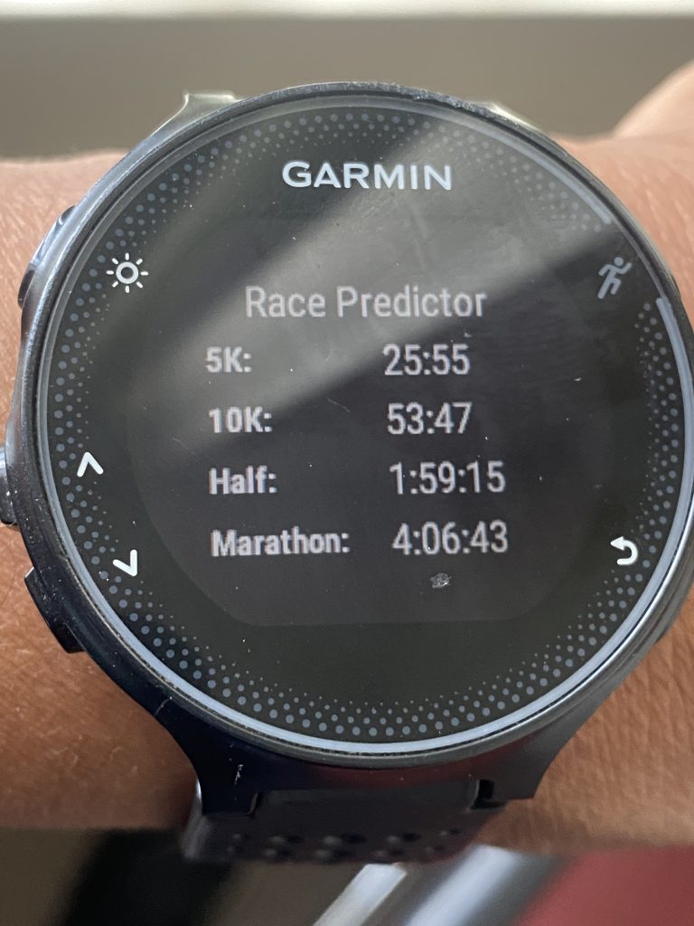 Garmin watch display showing race predictor with estimated finish times from 5K to Marathon.